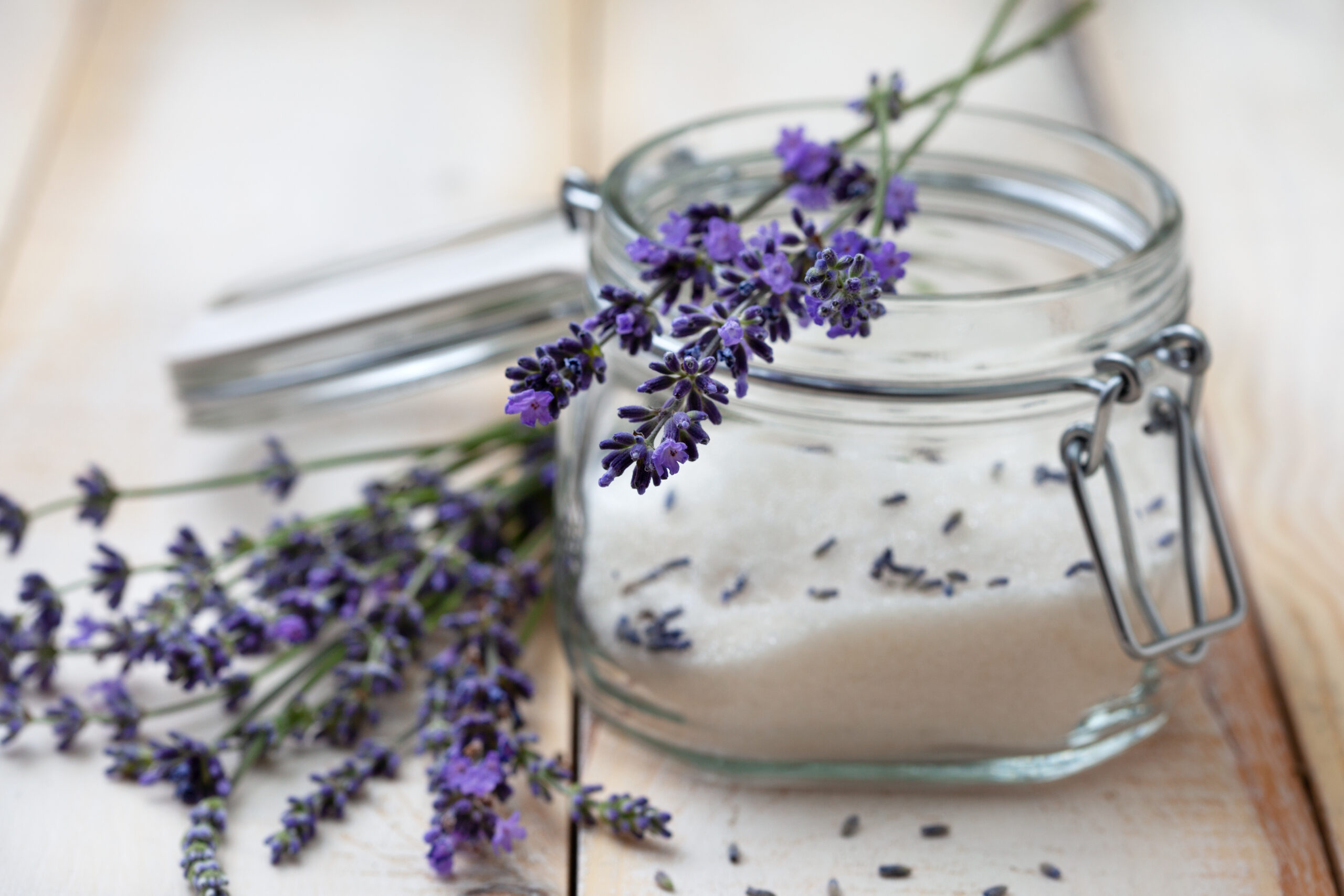 lavendar flower flavored sugar in a jar with fresh sprigs nearby