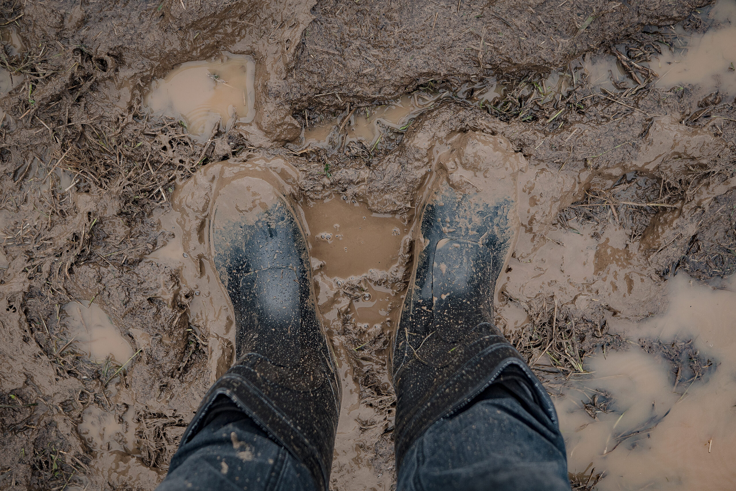 person wearing mud boots in mud and puddles